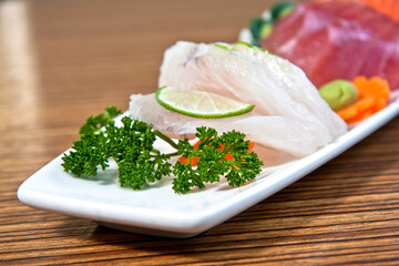 Mixed sliced fish sashimi on white plate Salmon, fish and tuna sashimi on wooden background