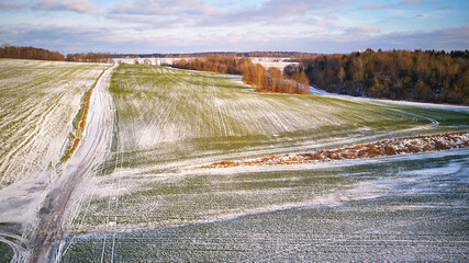 Winter Agricultural field under snow. Aerial scene. December Rural landscape. Countryside road