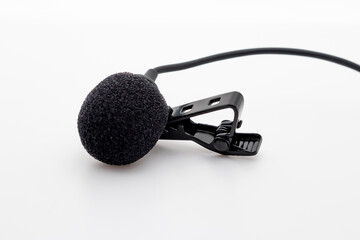 Lavalier or lapel microphone on a white surface, very close-up. The details of the grip clip or bra...