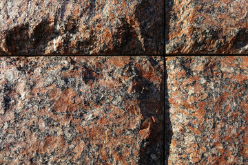 Red granite bricks masonry wall with grooves in the shape of a cross