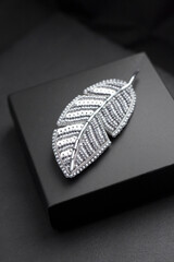 Beaded feather shape brooch on black background