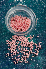 A glass jar full of pink sprinkles on a blue background