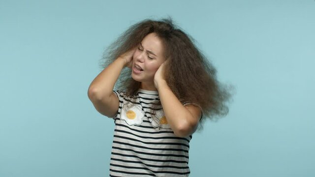 Ignorant woman unwilling to listen, shaking head in denial and shut ears with hands, cant hear you, standing over blue background