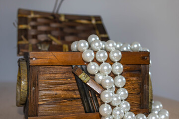 Few beads of pearls hanging on a vintage jewelry box on white background