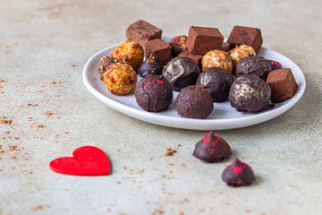 Variety of sweet homemade chocolate candies and truffles, light concrete background.
