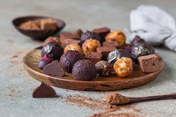 Variety of sweet homemade chocolate candies and truffles, light concrete background.