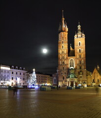Fototapeta na wymiar Night cityscape of Krakow old town, saint marys church, Christmas tree decorates main market square, full moon