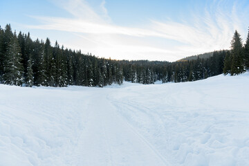 Fototapeta na wymiar Empty snowy path in a beautiful winter mountain landscape at sunset