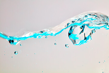 Nahaufnahme einer blauen Welle und Luftblasen vor hellem Hintergrund.