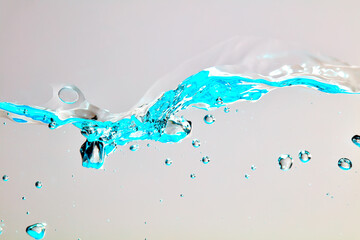 Nahaufnahme einer blauen Welle und Luftblasen vor hellem Hintergrund.