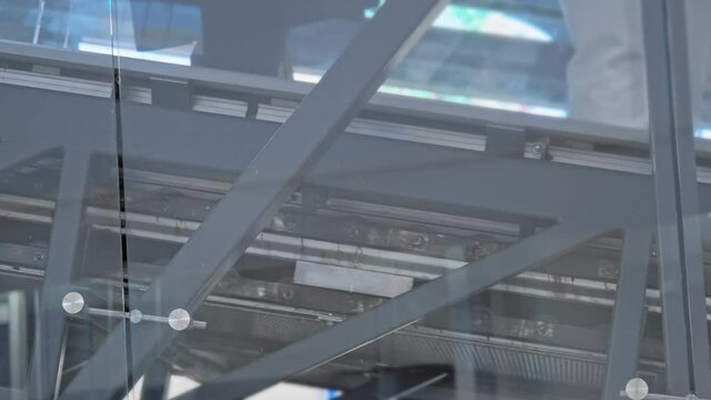 Escalator walkways going up and down. Through the glass you can see the moving rollers of the mechanisms
