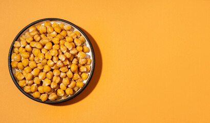 Chickpeas in small yellow ceramic plate bowl isolated on beige orange background.vegetarian dish. style minimalism banner.