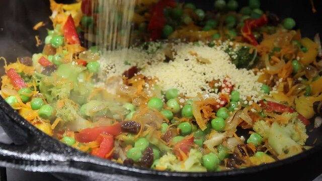 Putting Moroccan couscous in pan with vegetables