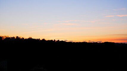 Pink and purple sunset sky with clouds painted in dark tones of blue.
