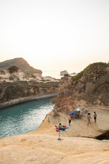 Canal D 'Amour beach in Corfu island with tourists. People have fun and relax on the rocks overlooking the sea, a real natural swimming pool