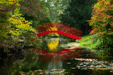 Puente rojo en el parque con reflejos sobre el agua del río