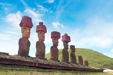 Stone structure and Moai statues at the Ahu Nao-Nao ceremonial center, at the Anakena beach on Easter Island, against a blue sky.