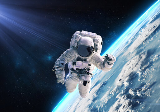 Science fiction walpaper of a lonely astronaut in free spacewalk orbit Earth planet globe with glow and nebulae on the background. Elements of this image furnished by NASA