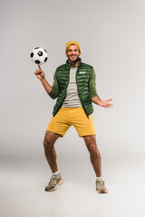 Sportsman smiling at camera while holding football on finger on grey background