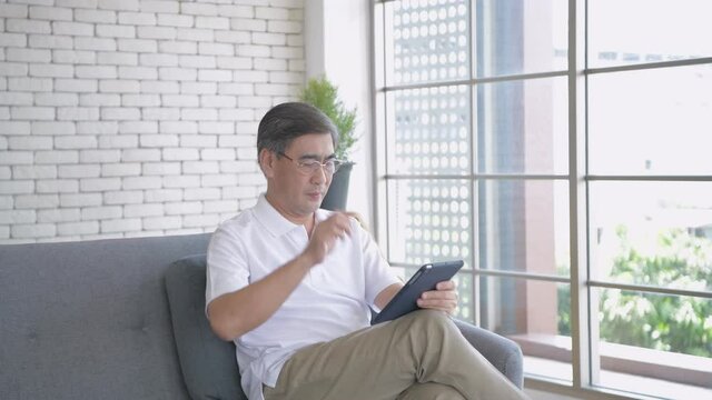 Health concept of 4k Resolution. A middle-aged Asian man is suffering from eye strain due to his long-time looking at the tablet.
