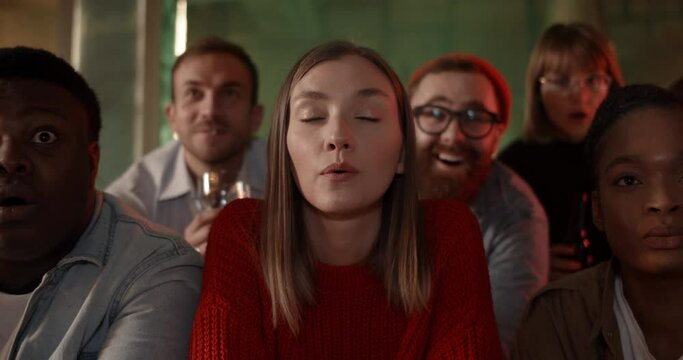 Excited diverse friends looking at tv screen with interest while watching sport game on TV. Cheerful group of friends spending time to while sitting at table with beer and supporting team