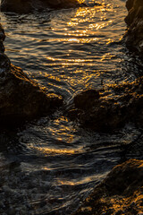 Alba / tramonto sul mare, rocce e scogliere escono dall'acqua con riflessi dai colori caldi, ora...