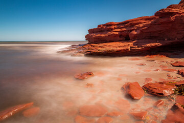 Long exposure of a clear sunny day at Canada's Prince Edward Island red sandstone cliff, next to the Atlantic ocean.