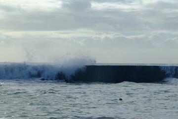 A wave breaking against the jetty at batz-sur-mer harbour. (west of France, december 2020)