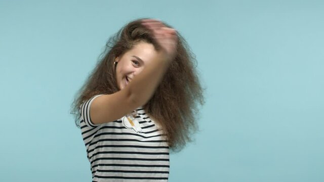 Slow motion of beautiful glamour girl pointing at camera, then beckon everyone come with me, inviting to party, smiling friendly, standing over blue background