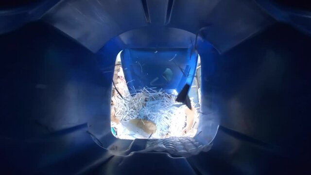 View inside recycling trash can being dumped into garbage truck.