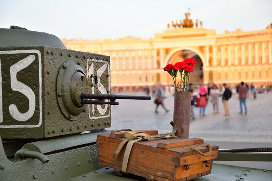 Red carnations in a gun case and box of shells at a small Soviet amphibious tank T-38 in the background of the Headquarters ' Arch