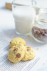 Chocolate chip cookies served with milk on rustic background