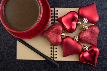 notebook for writing plans Christmas decorations hearts and a red cup of coffee on a black...