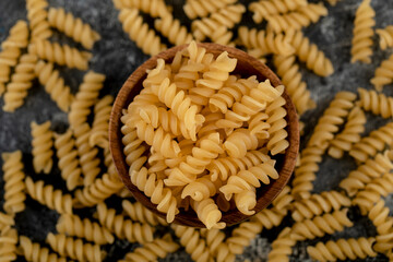Bowl of raw fusilli pasta on marble background