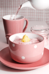 Sweet, pink oatmeal porridge with butter and tea is poured, for breakfast. Selective focus
