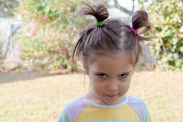 Cute little girl walks on nature and laughs and grimaces looking into the camera. happy childhood and positive emotions. 