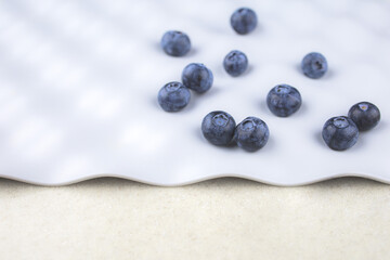 blue blueberries are scattered in a chaotic order on a gray background with space for text, close-up, blur
