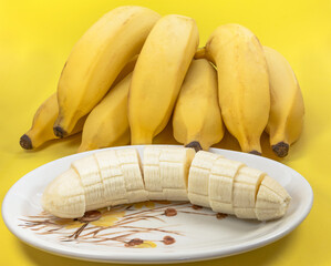 Close up de banana com casca e sem casca cortada no pires.