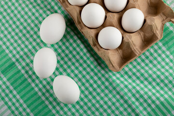 Carton of white eggs on striped tablecloth