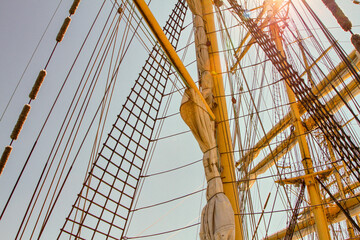 mast of a sailing ship against the sky. The sails have been removed. Rays, stairs, running rigging on the barge. day. Summer. Sunny.