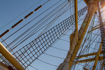 Fototapeta premium mast of a sailing ship against the sky. The sails have been removed. Rays, stairs, running rigging on the barge. day. Summer. Sunny.