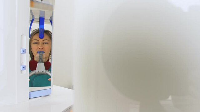 Doctor to take a image 3d scanner tomography of teeth and jaw in modern laboratory dental clinic. Female nurse shows the patient woman an x-ray machine 3d digital scanner. Computer dental diagnostics.
