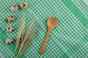 Quail eggs and ears of wheat on striped tablecloth