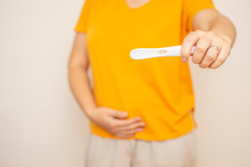 Closeup of woman hold positive pregnancy test. Pregnancy test with two stripes. Baby is coming. New life and maternity leave concept.