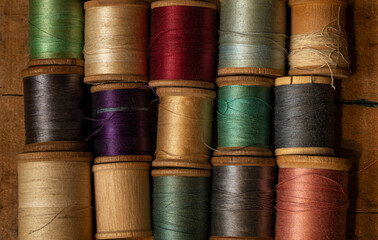 Spools of colorful vintage thread on wooden background