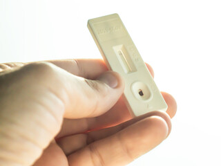Close-up of a hand holding a negative antigen test with white background. Selective focus.
