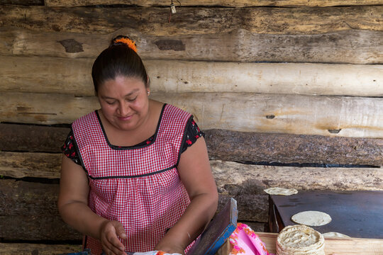 A Closeup Portrait Hispanic Woman In An Apron Preparing Traditional Mexican Tortillas In An Outdoors Kitchen