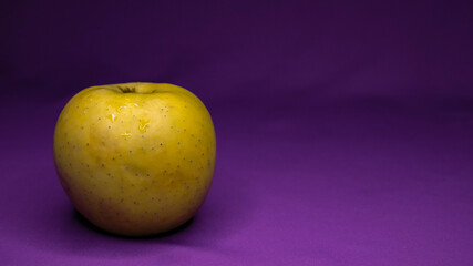 Alimentos saludables. Manzana amarilla sobre un fondo color púrpura con espacio para texto 