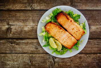 Roasted salmon fillet with green salad on gray plate.