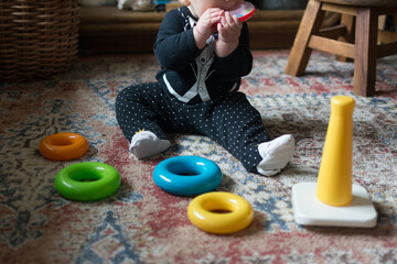 6 month old baby wearing tuxedo top playing with ring stacking toy